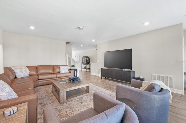 living area with light wood-type flooring, visible vents, and stairway