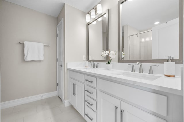 bathroom with double vanity, a shower stall, baseboards, and a sink