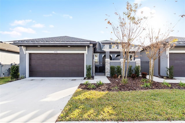 prairie-style house featuring an attached garage, fence private yard, concrete driveway, a gate, and stucco siding