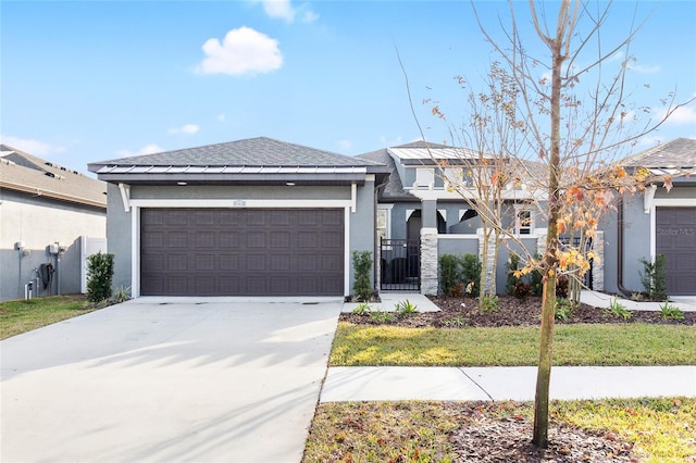 prairie-style house featuring a fenced front yard, driveway, an attached garage, and stucco siding