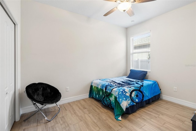 bedroom with a ceiling fan, a closet, light wood-style flooring, and baseboards