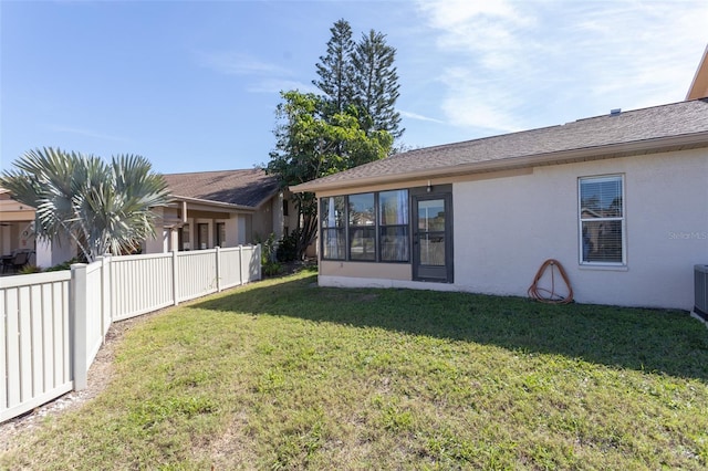 back of house with a yard, fence, and stucco siding