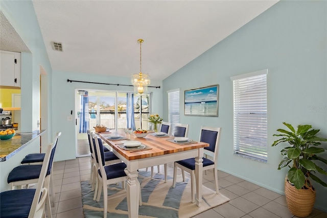 dining room with lofted ceiling, an inviting chandelier, visible vents, and light tile patterned flooring