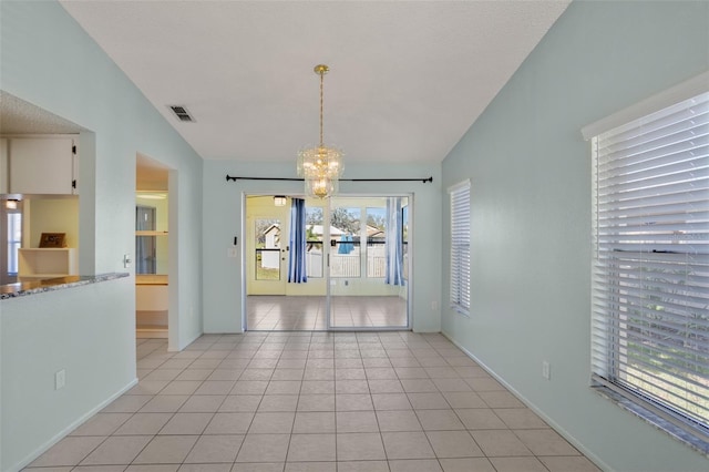 empty room with lofted ceiling, light tile patterned floors, a notable chandelier, visible vents, and baseboards