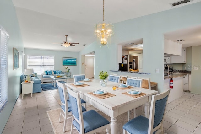 dining space with light tile patterned floors, ceiling fan with notable chandelier, and visible vents