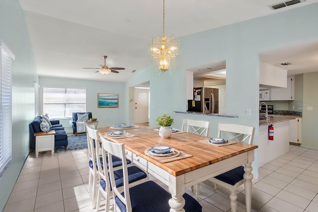 dining room with lofted ceiling, light tile patterned floors, visible vents, and ceiling fan with notable chandelier