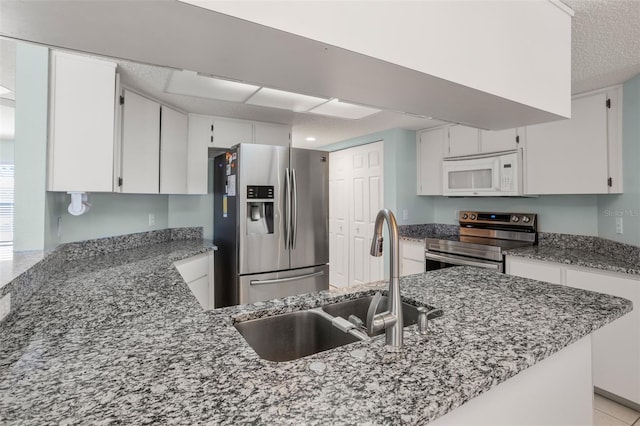 kitchen with stainless steel appliances, stone countertops, a sink, and white cabinets