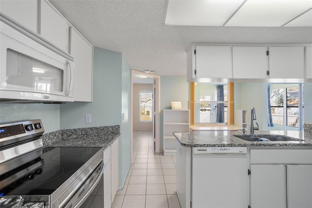 kitchen featuring light tile patterned floors, a textured ceiling, white appliances, a sink, and white cabinetry