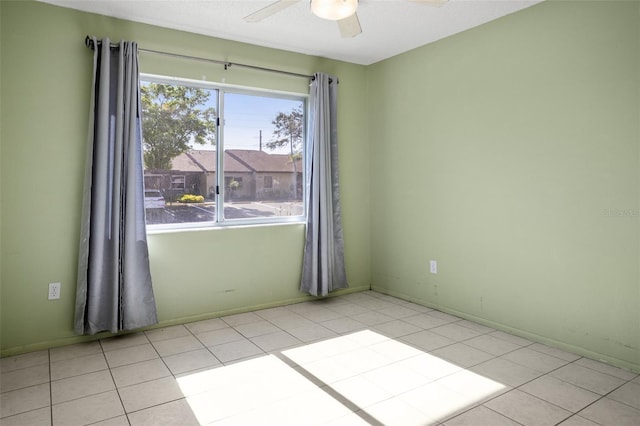 tiled spare room featuring a ceiling fan and baseboards