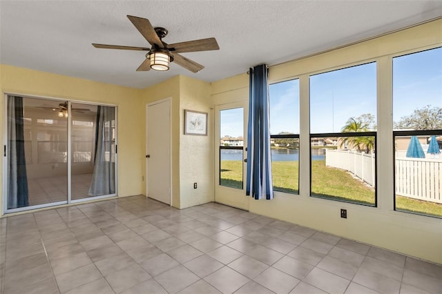 unfurnished sunroom with ceiling fan and a water view