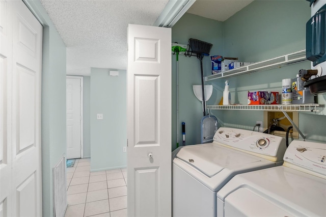 laundry area with washer and dryer, laundry area, a textured ceiling, and light tile patterned floors