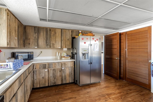 kitchen featuring a toaster, stainless steel fridge with ice dispenser, dark wood-style flooring, light countertops, and a sink