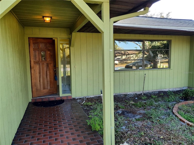 view of exterior entry with roof with shingles