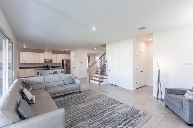 living room with light tile patterned floors, visible vents, baseboards, stairway, and recessed lighting