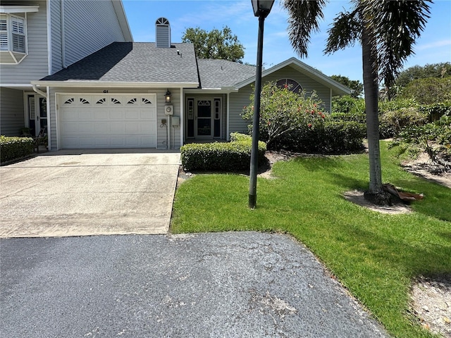 11722 Currie Ln Unit G1, Largo, FL 33774 - view of front of property with a garage, a front yard, concrete driveway, a shingled roof, and a chimney