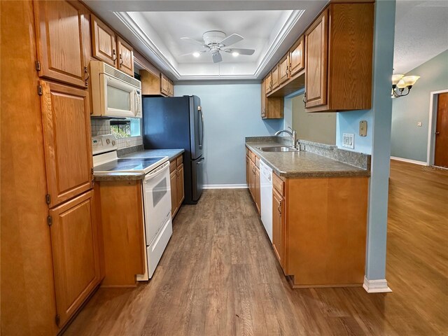 11722 Currie Ln Unit G1, Largo, FL 33774 - kitchen featuring white appliances, wood finished floors, a ceiling fan, brown cabinets, and a tray ceiling