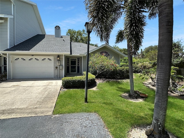 11722 Currie Ln Unit G1, Largo, FL 33774 - view of front facade featuring a shingled roof, an attached garage, a front yard, concrete driveway, and a chimney