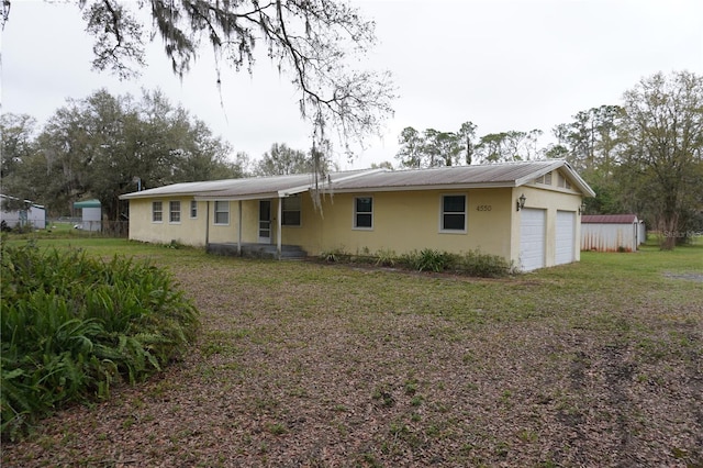 view of front of property featuring metal roof, an attached garage, fence, stucco siding, and a front yard