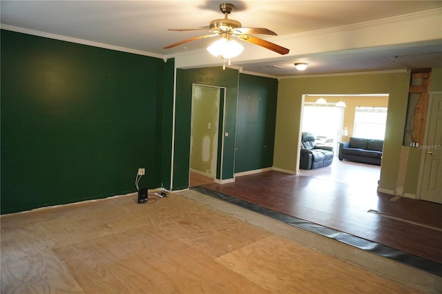 unfurnished room with ornamental molding, a ceiling fan, baseboards, and wood finished floors