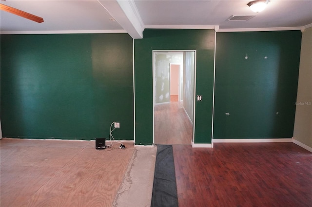 spare room with wood finished floors, a ceiling fan, baseboards, visible vents, and crown molding