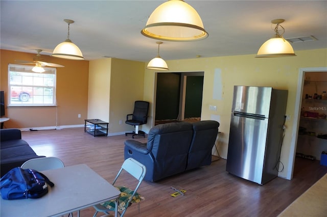 living area with visible vents, baseboards, and wood finished floors