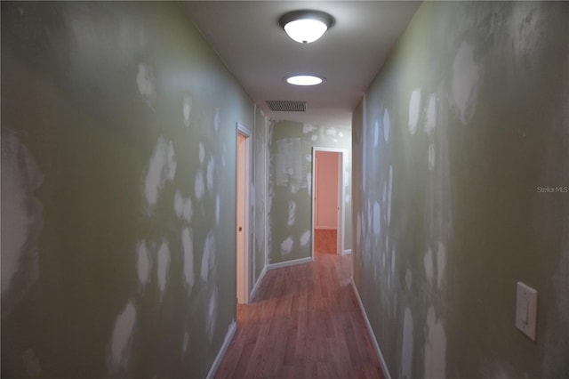 corridor with baseboards, visible vents, and wood finished floors