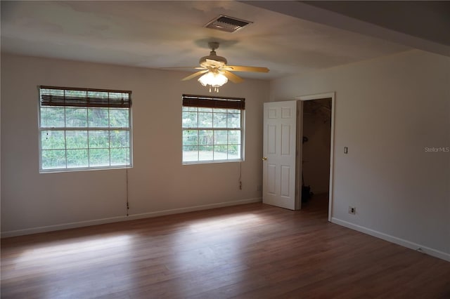 spare room featuring baseboards, visible vents, ceiling fan, and wood finished floors