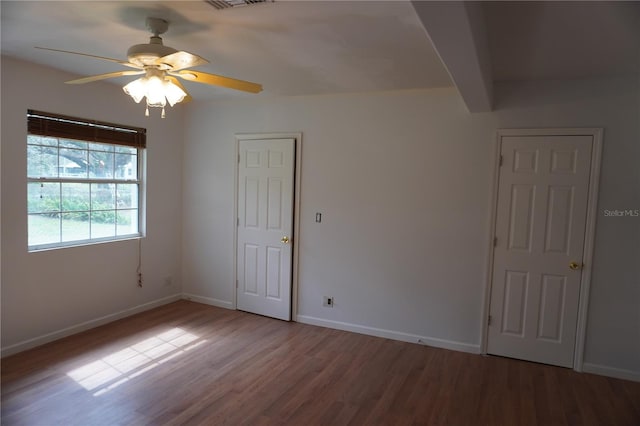 unfurnished room featuring visible vents, wood finished floors, a ceiling fan, and baseboards