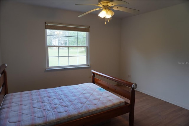 bedroom with ceiling fan, baseboards, and wood finished floors