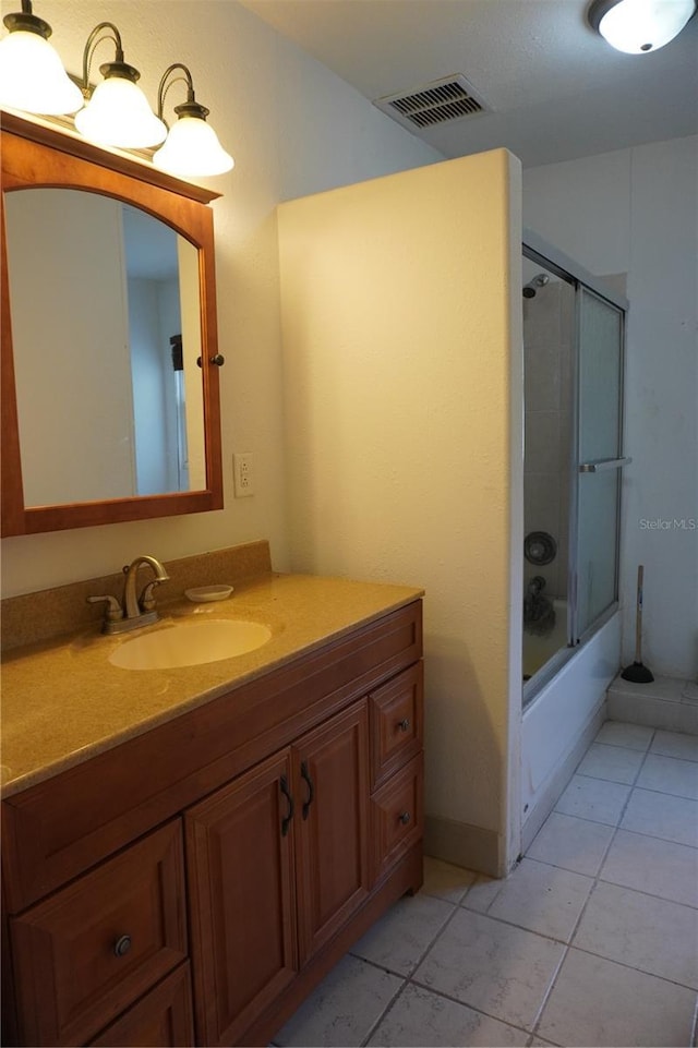 full bathroom with bath / shower combo with glass door, vanity, visible vents, and tile patterned floors