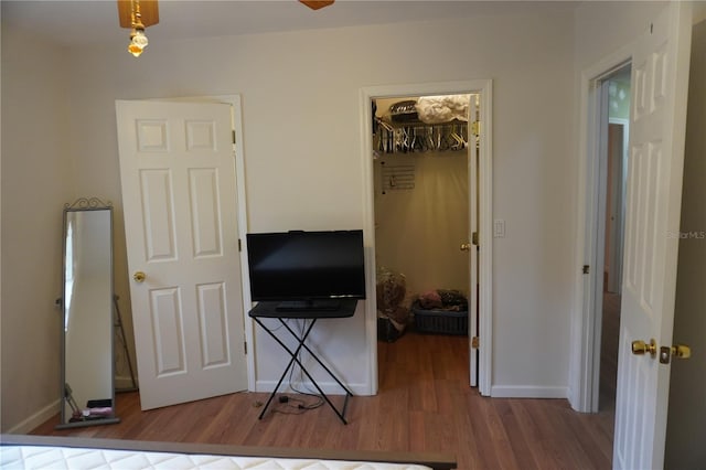 bedroom with a closet, a spacious closet, baseboards, and wood finished floors