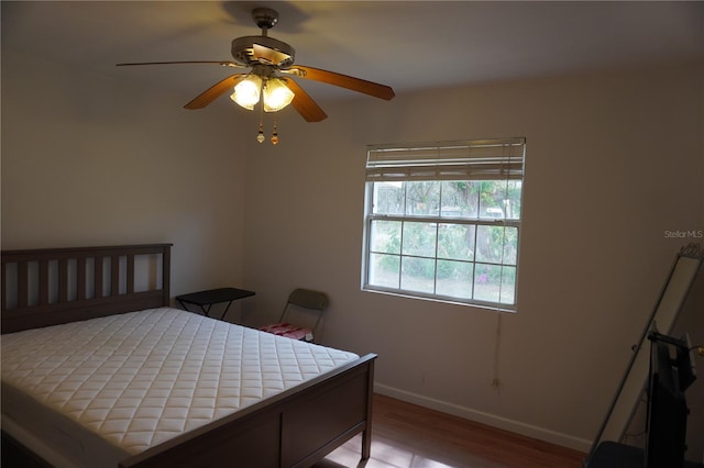 bedroom with a ceiling fan, baseboards, and wood finished floors