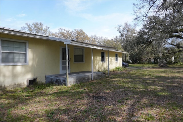 back of property featuring a patio area, metal roof, a lawn, and stucco siding