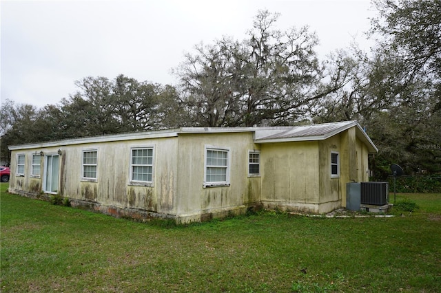 view of property exterior featuring metal roof, central AC, and a lawn