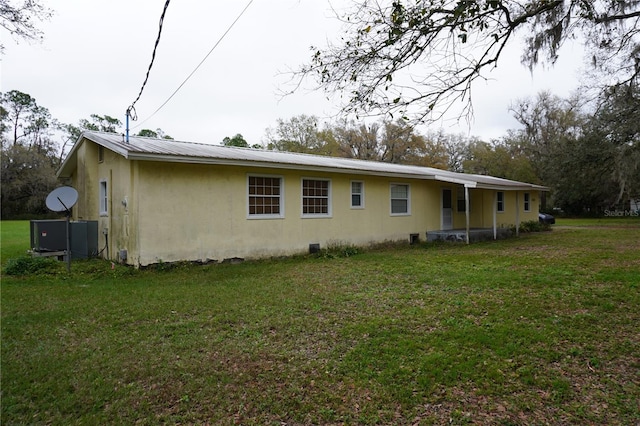 back of house featuring metal roof, a yard, and stucco siding