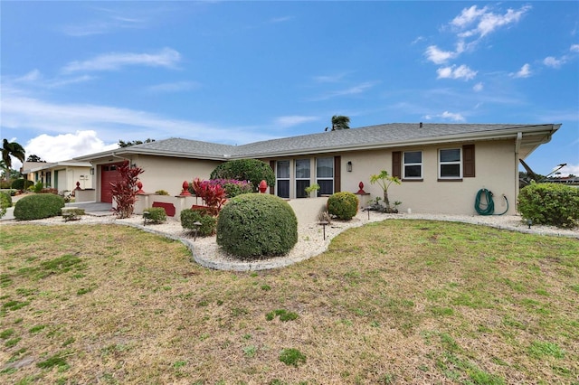 ranch-style home with a garage, a front yard, and stucco siding