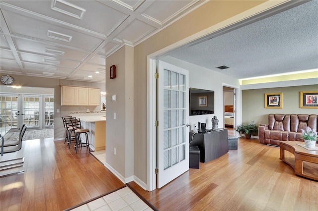 living room with visible vents, coffered ceiling, light wood-style flooring, and baseboards