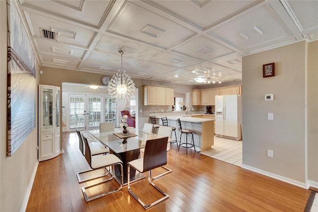 dining area with light wood finished floors, baseboards, coffered ceiling, and french doors