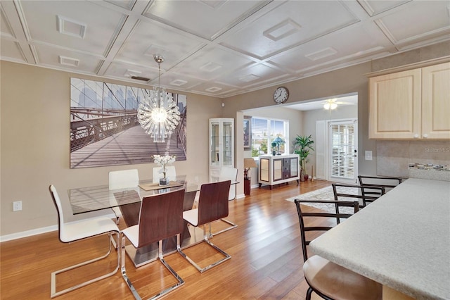 dining space featuring baseboards, visible vents, coffered ceiling, an inviting chandelier, and light wood-style floors