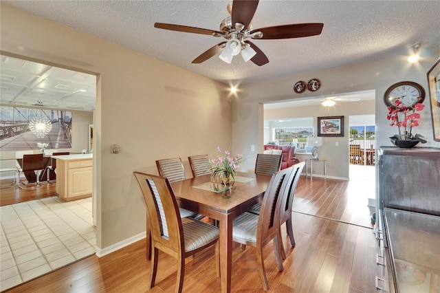 dining space with light wood-type flooring, baseboards, and a textured ceiling