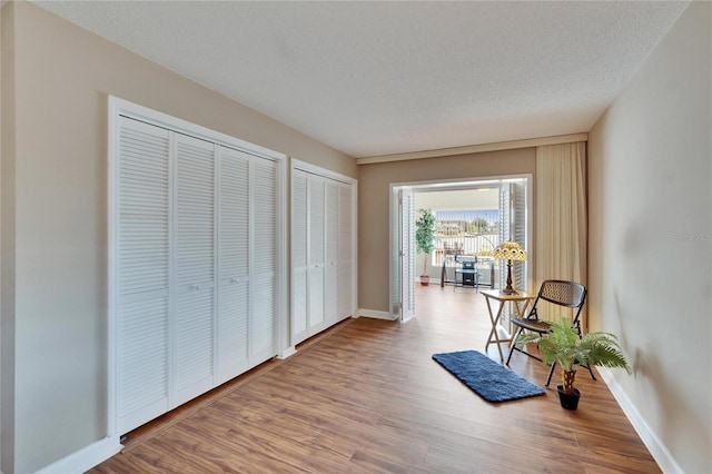 sitting room with a textured ceiling, baseboards, and wood finished floors