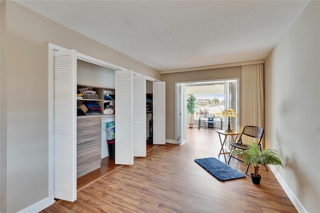 living area with a textured ceiling, baseboards, and wood finished floors