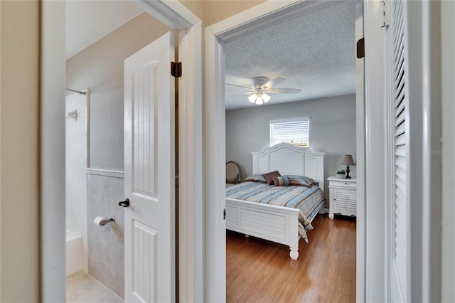 bedroom featuring a textured ceiling, wood finished floors, and a ceiling fan