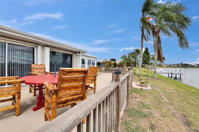 wooden terrace featuring a water view and a lawn