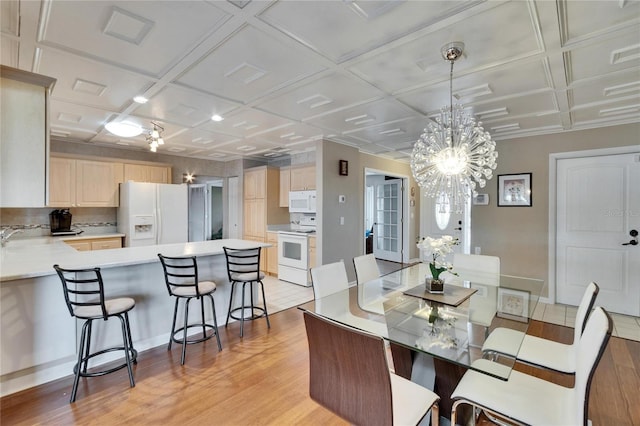 dining room featuring coffered ceiling, visible vents, a notable chandelier, and light wood finished floors