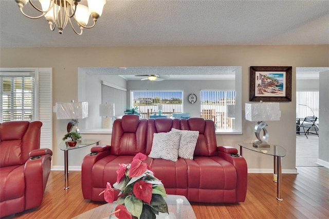 living area with plenty of natural light, a textured ceiling, baseboards, and wood finished floors