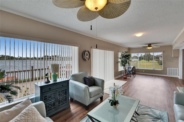 living area featuring ornamental molding, dark wood-style flooring, a water view, and visible vents