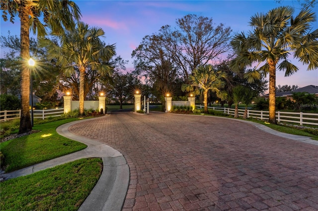 view of community with a fenced front yard and curved driveway