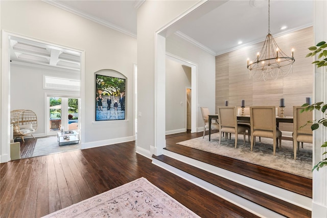 dining space with wood-type flooring, ornamental molding, a chandelier, coffered ceiling, and baseboards