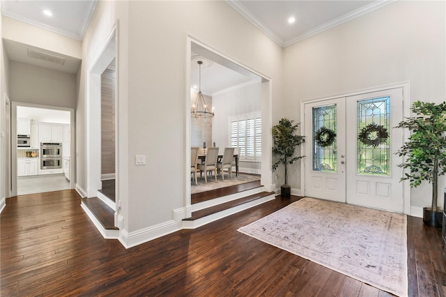 foyer featuring ornamental molding, a chandelier, dark wood finished floors, and baseboards